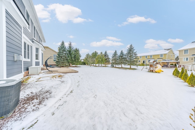 snowy yard featuring a playground and central AC unit