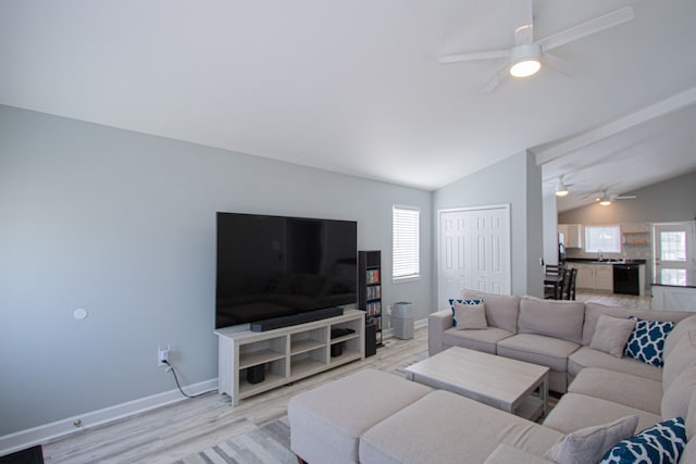 living room with ceiling fan, sink, light hardwood / wood-style floors, and vaulted ceiling