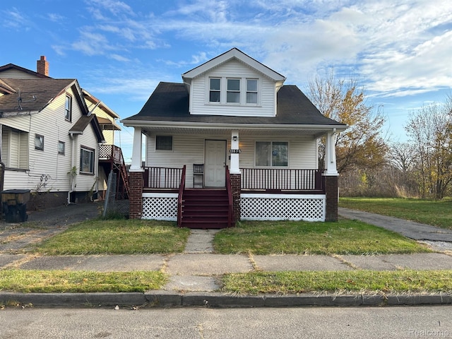 bungalow featuring covered porch and a front yard