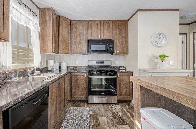 kitchen featuring dark hardwood / wood-style floors, sink, ornamental molding, black appliances, and a textured ceiling