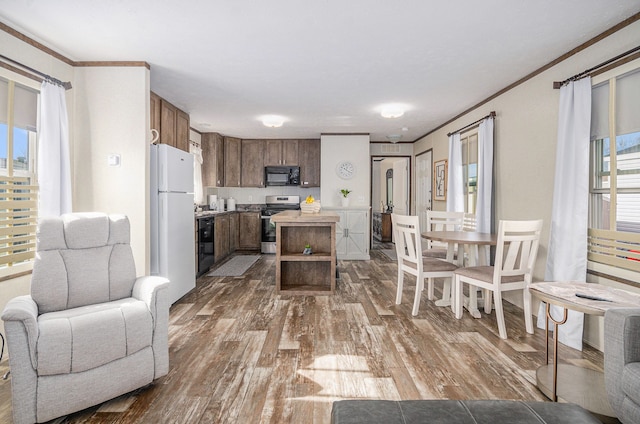 kitchen featuring ornamental molding, wood-type flooring, black appliances, and a kitchen island