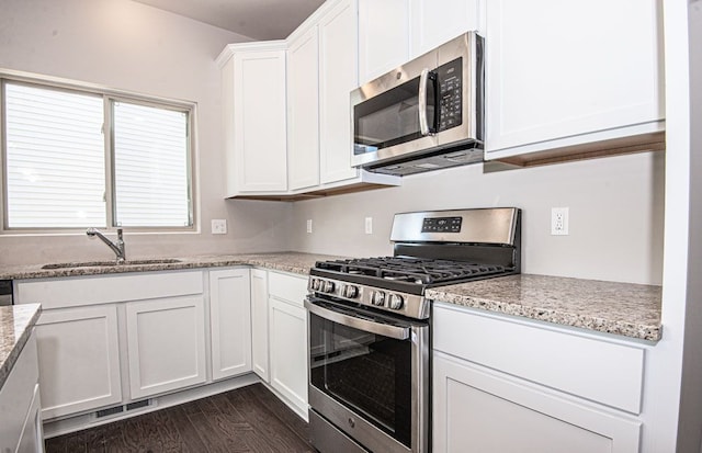 kitchen featuring appliances with stainless steel finishes, light stone countertops, sink, and white cabinets