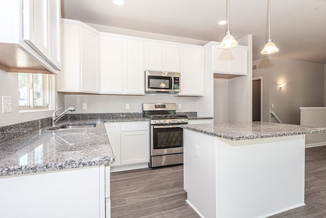 kitchen with a sink, appliances with stainless steel finishes, wood finished floors, and white cabinets