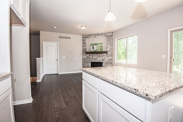 kitchen featuring visible vents, dark wood-type flooring, light stone counters, and white cabinets