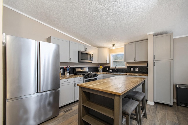 kitchen with dark wood-type flooring, appliances with stainless steel finishes, sink, and a textured ceiling