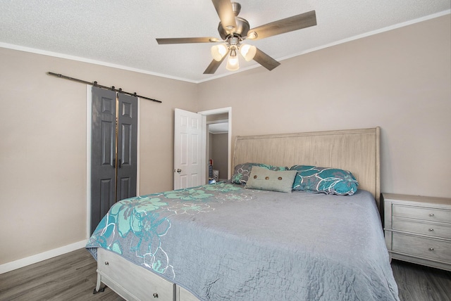 bedroom with crown molding, a textured ceiling, dark hardwood / wood-style floors, ceiling fan, and a barn door