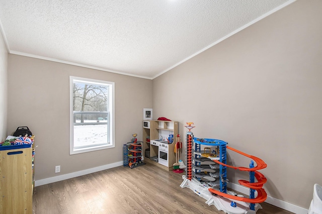 recreation room featuring ornamental molding, hardwood / wood-style floors, and a textured ceiling