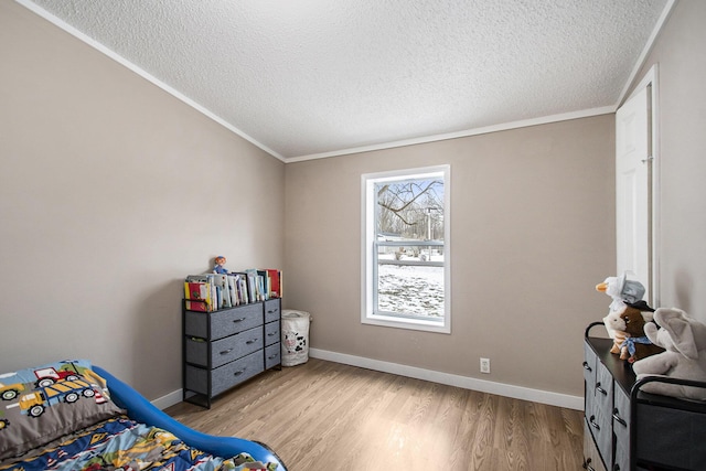 bedroom with crown molding, a textured ceiling, and light wood-type flooring