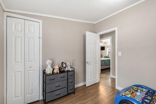 bedroom featuring crown molding, wood-type flooring, a closet, and a textured ceiling