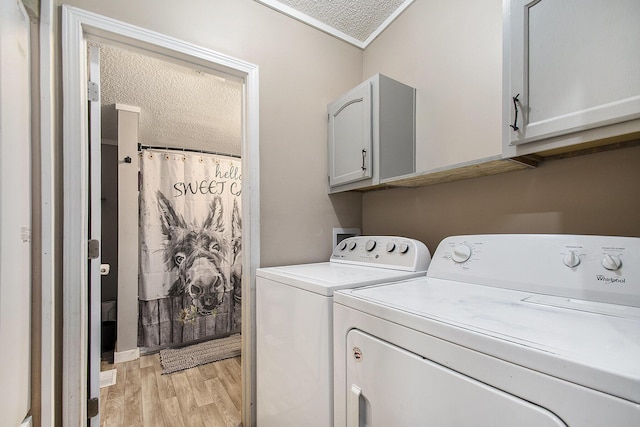 clothes washing area featuring cabinets, light wood-type flooring, a textured ceiling, and independent washer and dryer