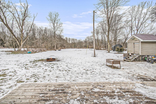 yard covered in snow featuring a storage unit and an outdoor fire pit