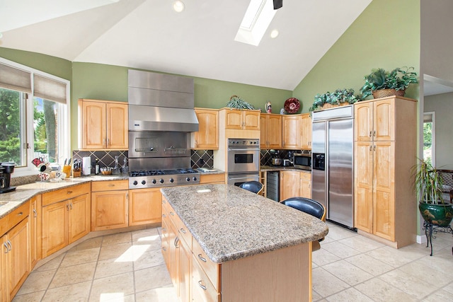 kitchen with a kitchen island, a skylight, range hood, stainless steel appliances, and light stone countertops