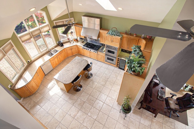 living room with ceiling fan, sink, high vaulted ceiling, and a skylight