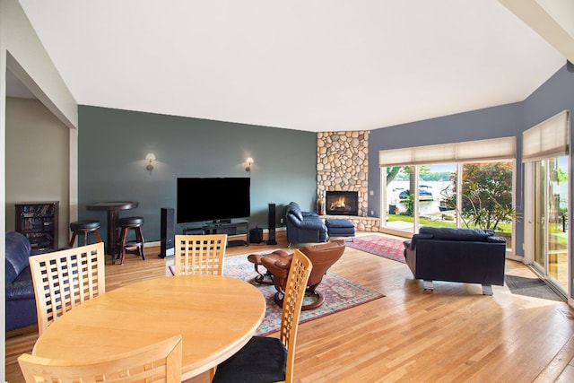 dining room featuring hardwood / wood-style flooring and a stone fireplace