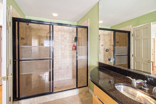 bathroom with walk in shower, vanity, and tile patterned flooring