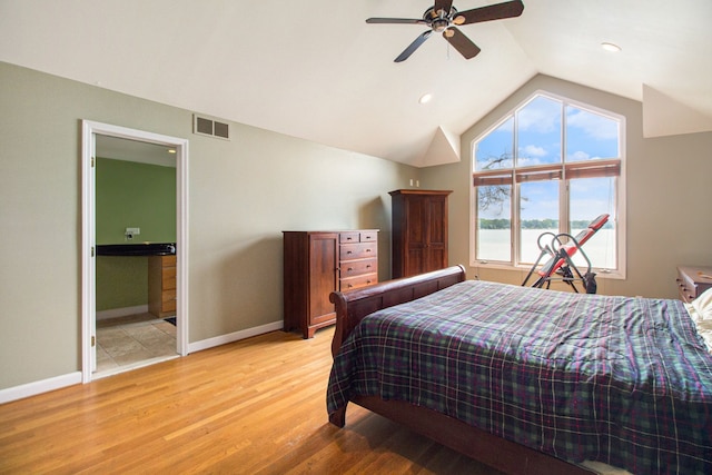 bedroom featuring ceiling fan, lofted ceiling, ensuite bathroom, and light hardwood / wood-style flooring