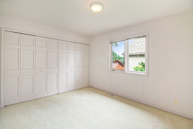 unfurnished bedroom featuring light carpet and a closet