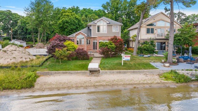 view of front of property with a water view, a balcony, and a front yard