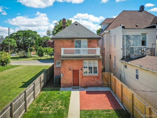 back of property with a balcony, central AC unit, and a lawn