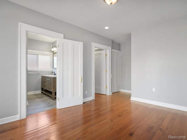 unfurnished bedroom featuring ensuite bathroom and light hardwood / wood-style flooring