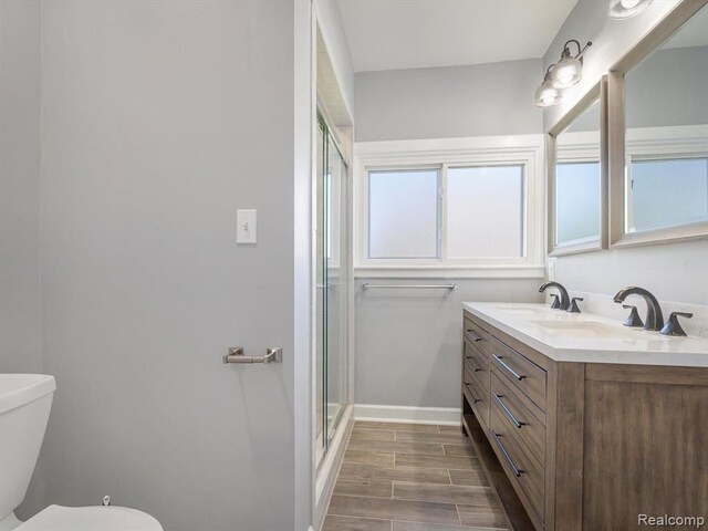 bathroom featuring a shower with door, vanity, and toilet