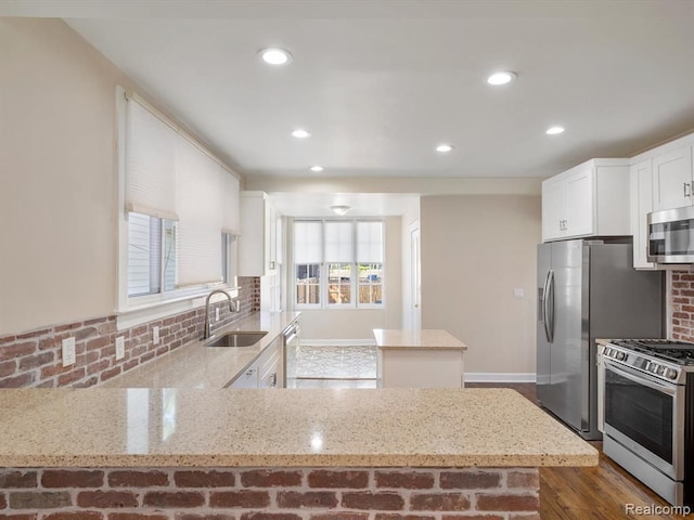 kitchen with white cabinetry, sink, backsplash, light stone counters, and stainless steel appliances