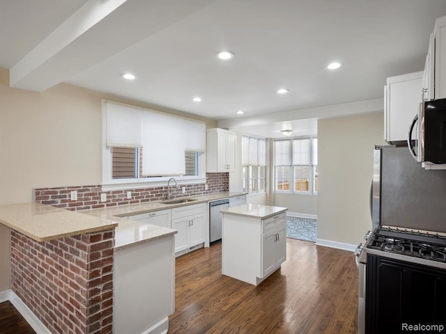 kitchen with white cabinetry, sink, light stone counters, kitchen peninsula, and stainless steel appliances