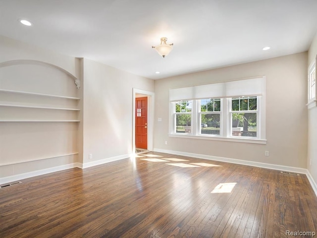 unfurnished living room featuring built in features and dark hardwood / wood-style floors