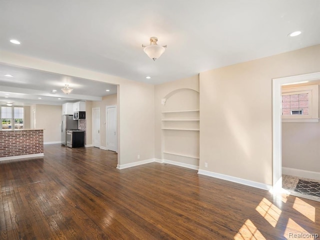 unfurnished living room with dark wood-type flooring and built in features