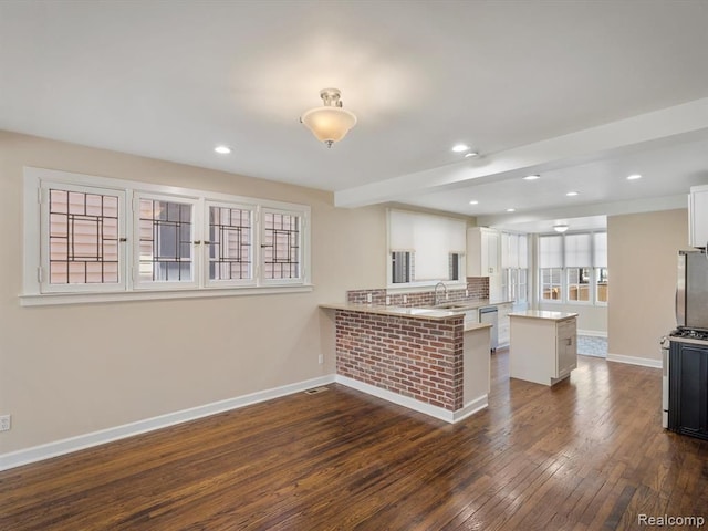 kitchen with dark wood-type flooring, white cabinetry, stainless steel appliances, a kitchen bar, and kitchen peninsula