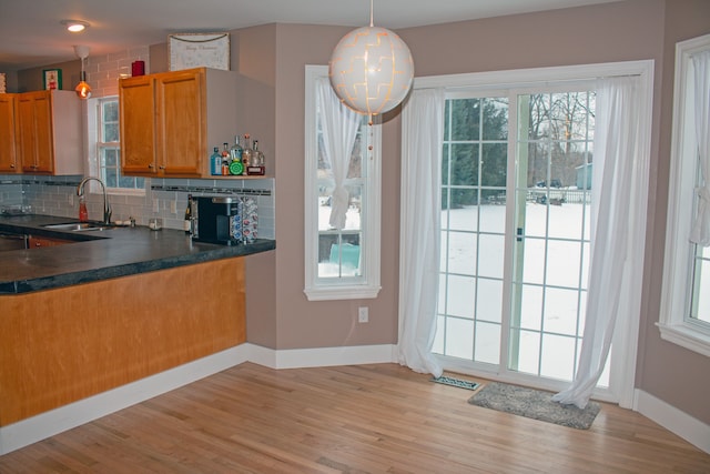 kitchen with sink, decorative backsplash, light wood-type flooring, and decorative light fixtures