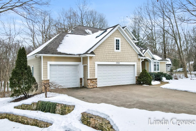 view of front facade featuring an attached garage, driveway, and stone siding