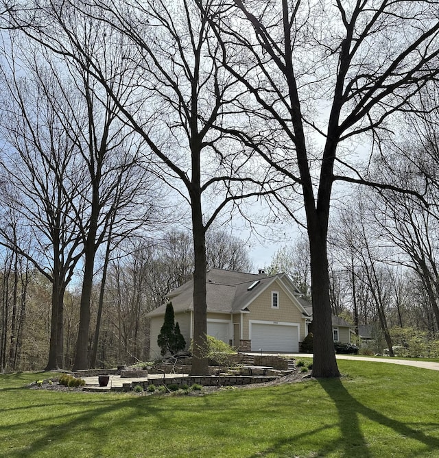 view of front of property featuring stone siding, an attached garage, and a front lawn