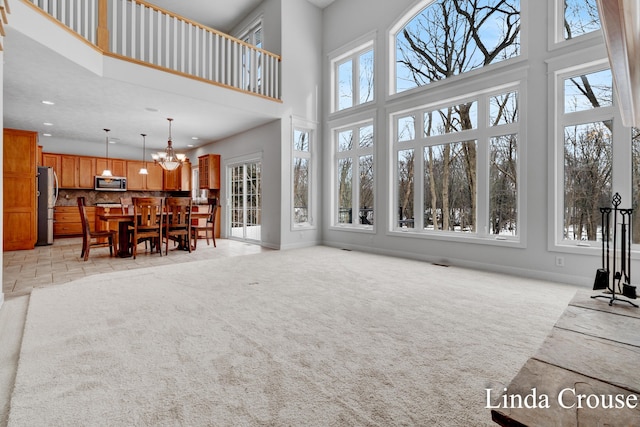 living area with baseboards, light colored carpet, a towering ceiling, an inviting chandelier, and recessed lighting