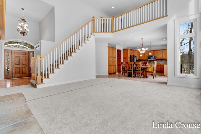 entrance foyer featuring a chandelier, light carpet, stairway, and a high ceiling