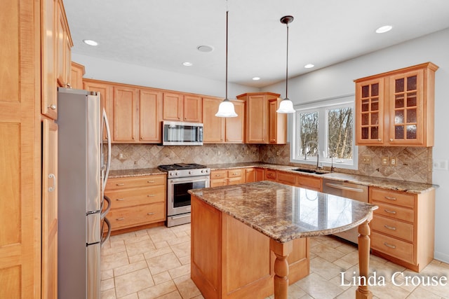 kitchen featuring a breakfast bar, a center island, appliances with stainless steel finishes, glass insert cabinets, and a sink