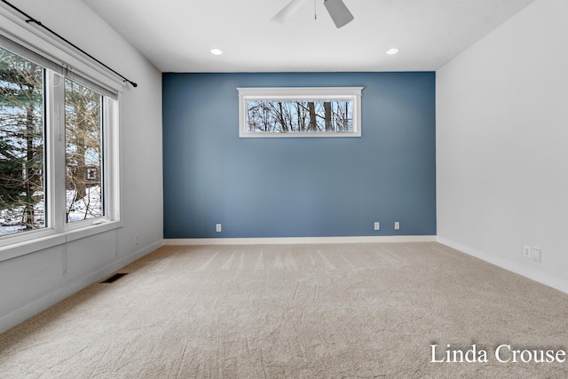 carpeted spare room with a healthy amount of sunlight, visible vents, and baseboards