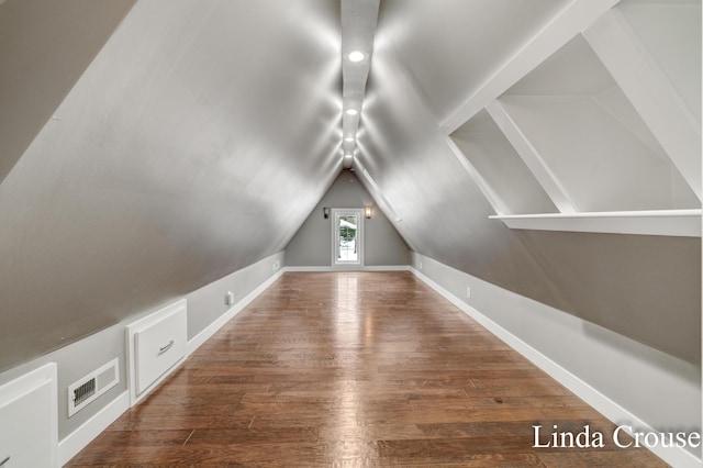 additional living space with lofted ceiling, visible vents, baseboards, and wood finished floors