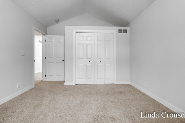 unfurnished bedroom with carpet, visible vents, lofted ceiling, and baseboards