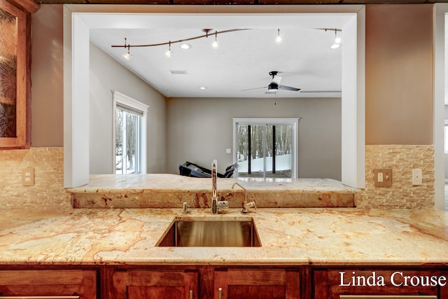 kitchen featuring visible vents, light stone counters, a sink, and a wealth of natural light