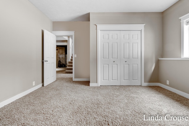 unfurnished bedroom with a closet, carpet flooring, and baseboards