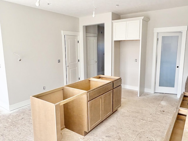 kitchen with white cabinetry, baseboards, and a kitchen island