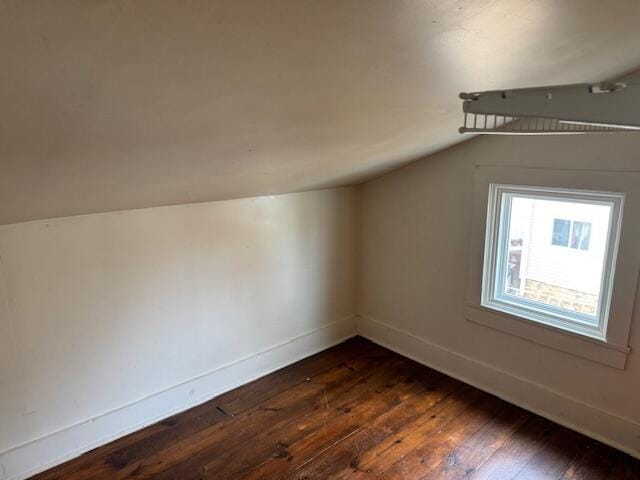 bonus room with dark wood-type flooring and vaulted ceiling