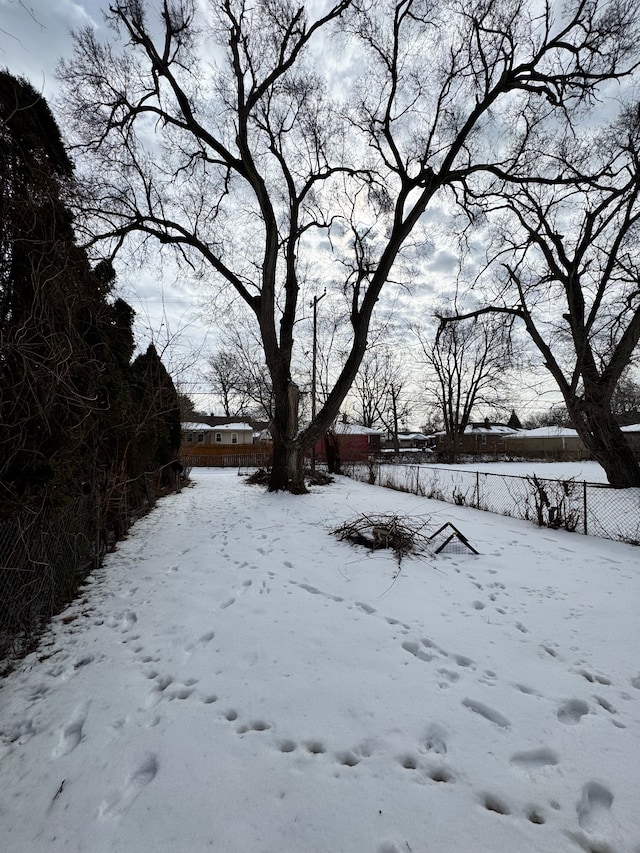 snowy yard with a garage and fence