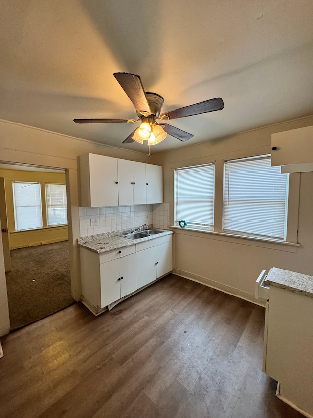 kitchen with tasteful backsplash, dark wood finished floors, light countertops, white cabinetry, and a sink