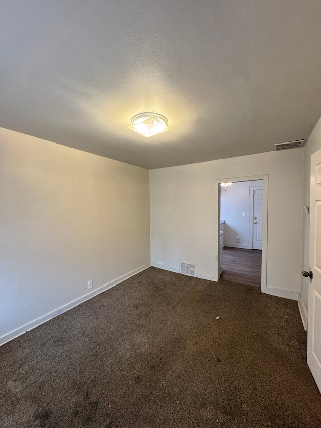 carpeted empty room featuring baseboards, visible vents, and a textured ceiling