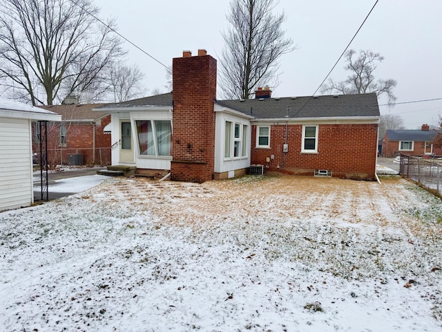 snow covered rear of property featuring central AC