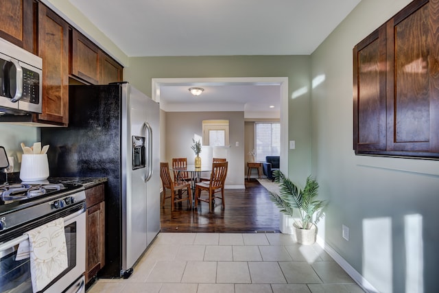 kitchen with dark brown cabinetry, light tile patterned floors, and stainless steel appliances