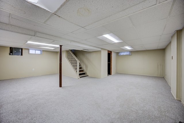 basement with light carpet, a paneled ceiling, and electric panel