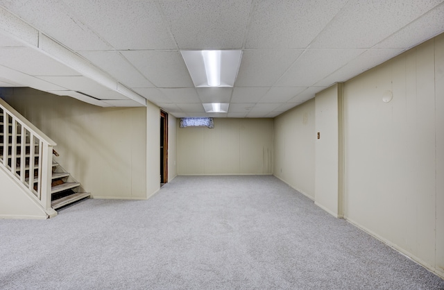 basement featuring a paneled ceiling and light colored carpet